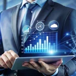 Homem de terno usando tablet com gráficos de crescimento e ícones de nuvem, ilustrando um conteúdo da Ramo sobre preço SAP Business One.